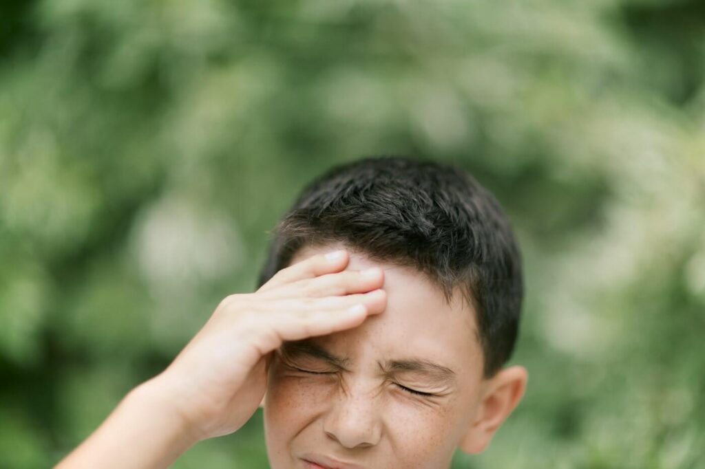 Boy touching his head in pain with headache