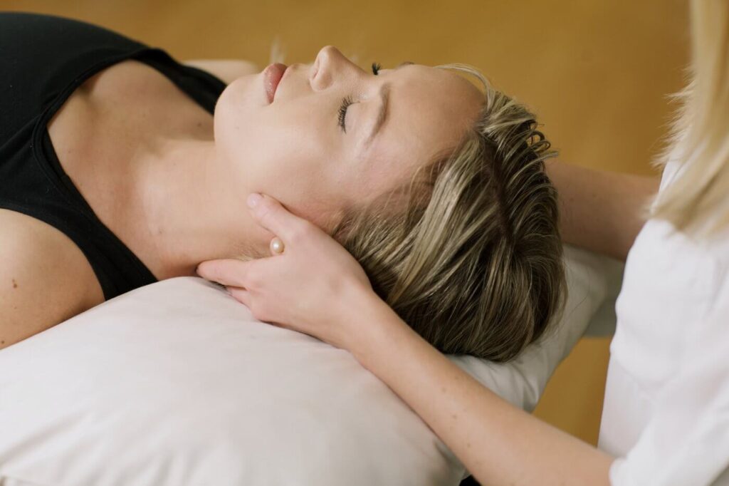 Woman lying down with eyes closed being assessed by chiropractor