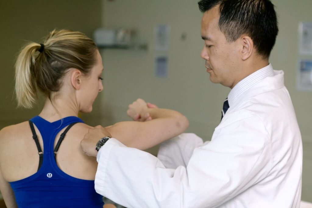 Chiropractor assessing shoulder range of motion on patient