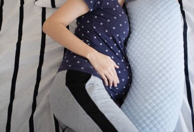 Pregnant woman sleeping on the side with pillow to relieve back pain
