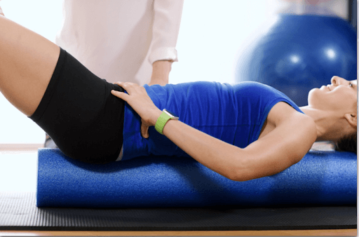 a woman is lying down on a foam roller and smiling