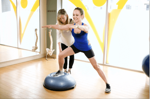 a physiotherapist is guiding a woman through an exercise on a bosu ball