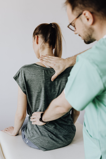male chiropractor in green scrub top working on a patient’s back