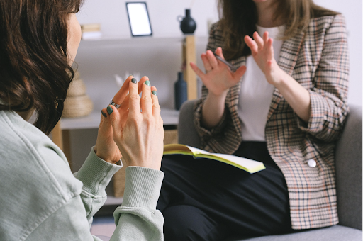 two women from the chin down sitting down and talking to each other