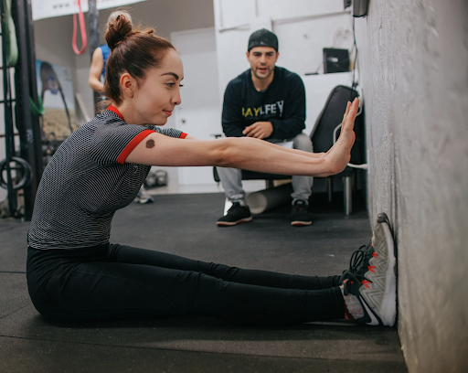 woman stretching toward wall while professional observes her