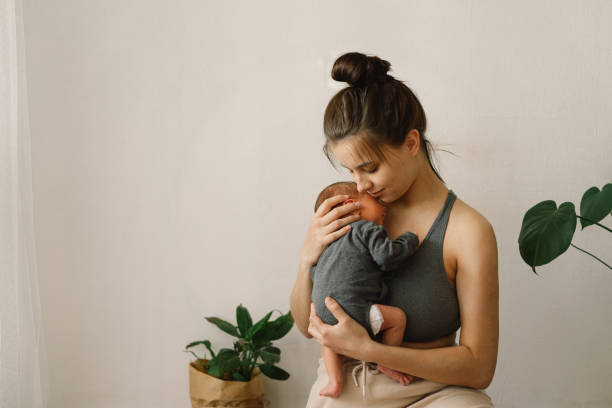 Mother holds and hugs her newborn baby son at home. Happy infant and mom