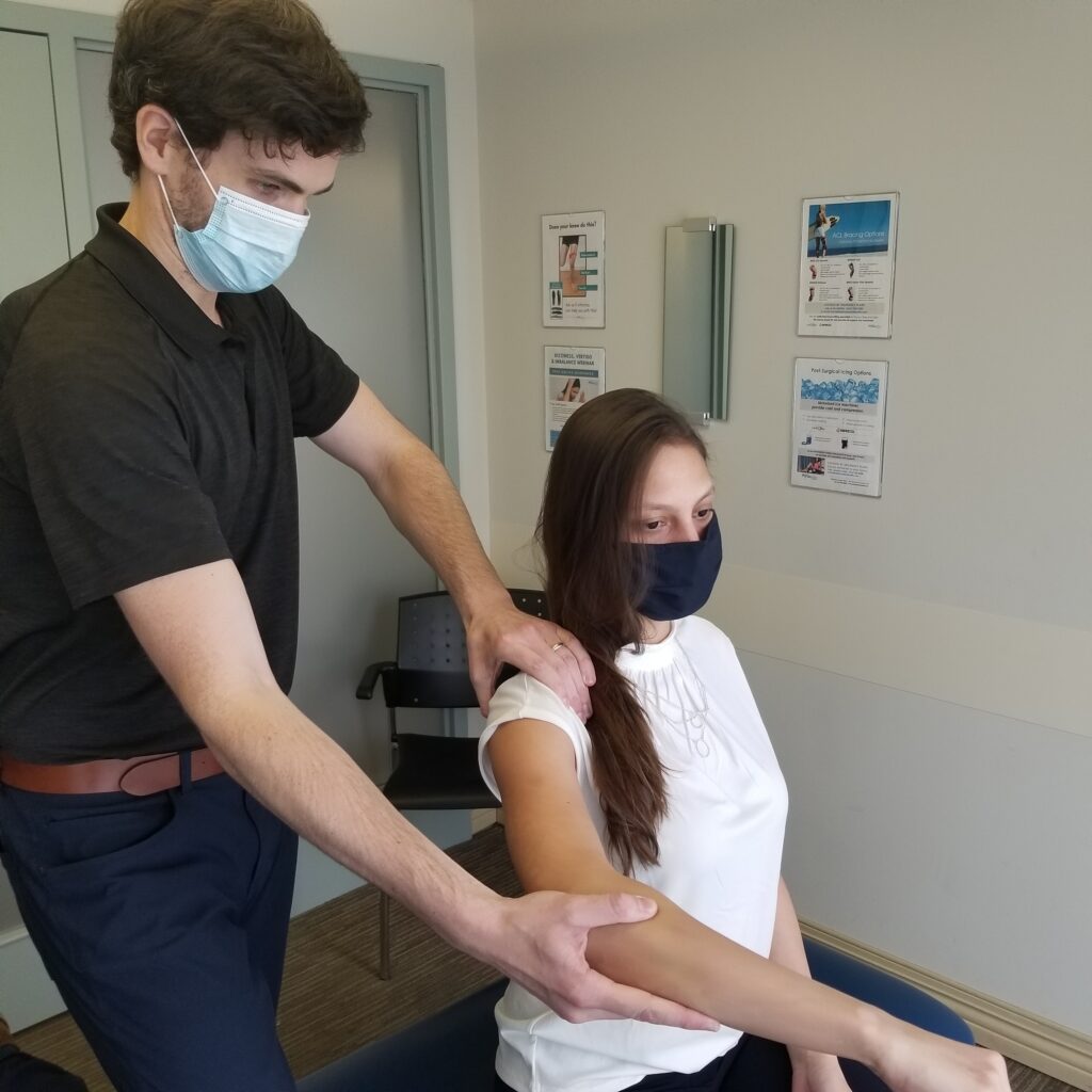 a chiropractor and physiotherapist helping a patient do a shoulder exercise