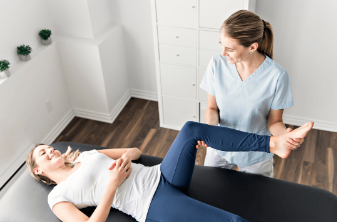 a physiotherapist lifting a woman’s leg during an in-home physiotherapy session